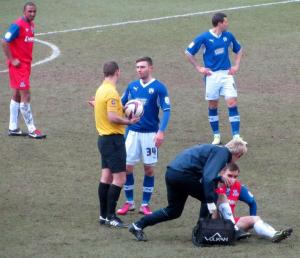 Jay O'Shea has a word with the referee as a Gillingham player receives treatment