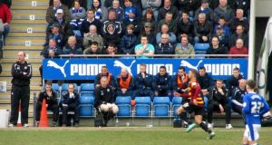 Paul Cook and the home dugout watch the early action