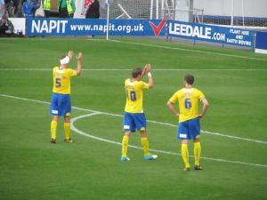 The Dons players applaud their supporters